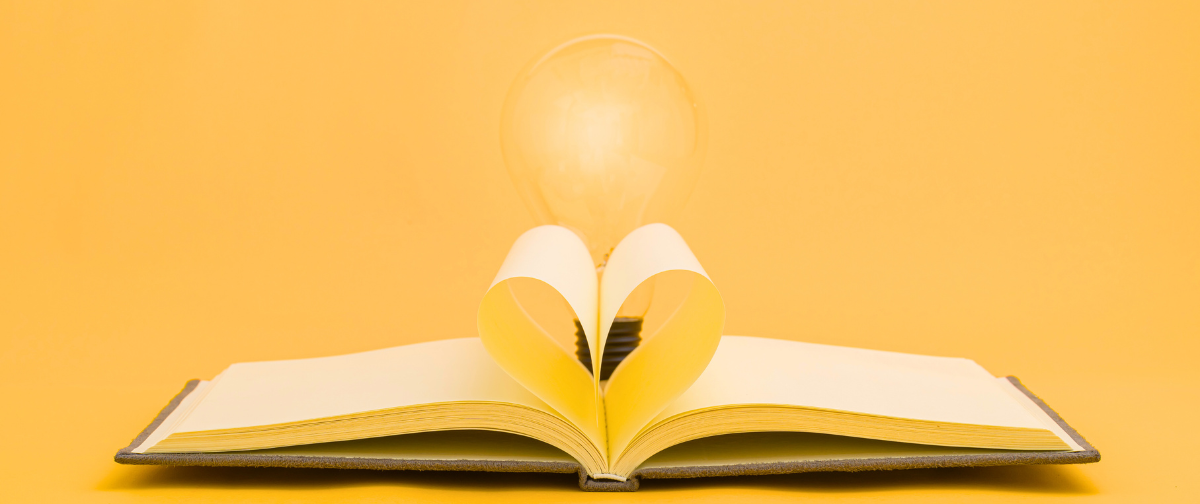 yellow background with a book whose pages are opened in the shape of a heart with a lightbulb